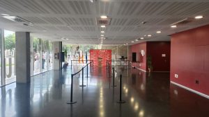 Vestíbulo de la Casa del Estudiante preparado para la jornada de acogida, con atril, banderas y photocall rojo de UPV PIAE+ al fondo