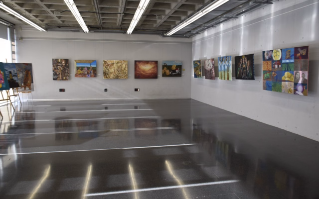 Exhibition room with paintings on the walls, several featuring potatoes, from the Patatas Lázaro creative challenge for Fine Arts students