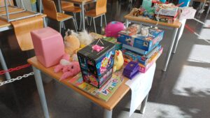 Mesa con juguetes donados en la campaña Un Juguete, una Sonrisa: una caja de Lego, peluches, puzles, juegos de mesa y un libro infantil