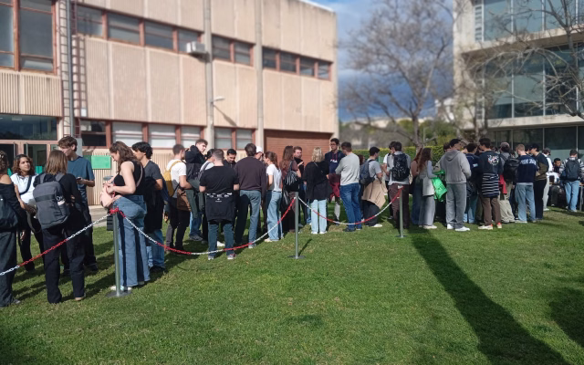 A large group of students queues behind rope barriers on the lawn of the Student Recreation Centre gardens during Welcome Day