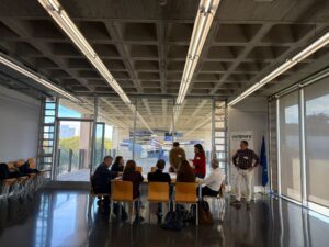 Participants working around a table during the European Visionary project session, beside its roll-up banner and the EU flag