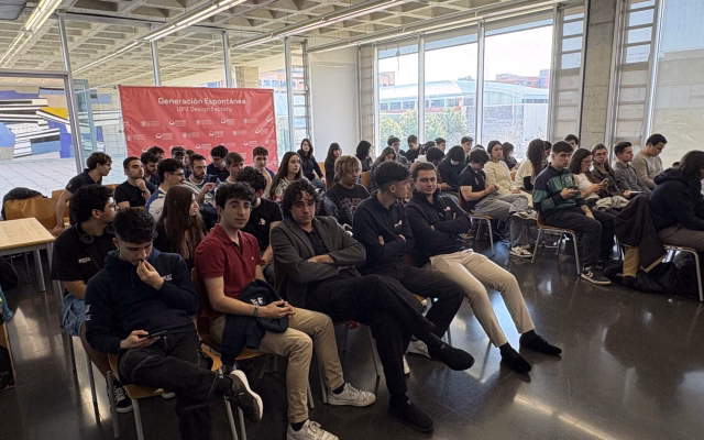 Estudiants dels grups de Generació Espontània asseguts a la sala Ximo Mora durant la trobada, amb la lona del programa al fons