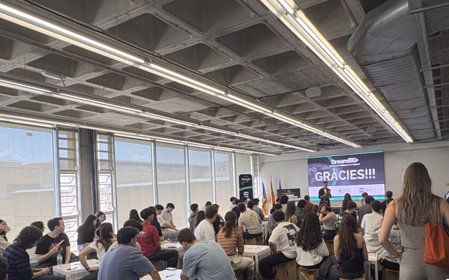 Students seated in the Ximo Mora room follow the closing of the Dream BIG 2026 Hackathon, with the stage screen reading Gràcies (thank you)