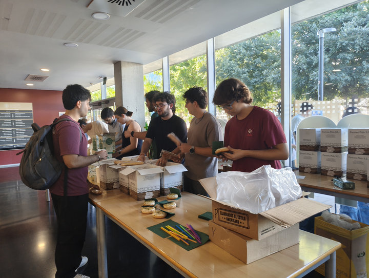 Estudiants preparen una taula amb fartons, dònuts i palletes de colors, al costat de caixes de fartons, a la planta baixa