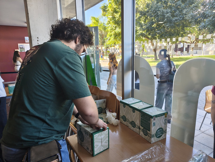 Un estudiant obri caixes d'orxata sobre una taula al costat de la façana de vidre de la planta baixa
